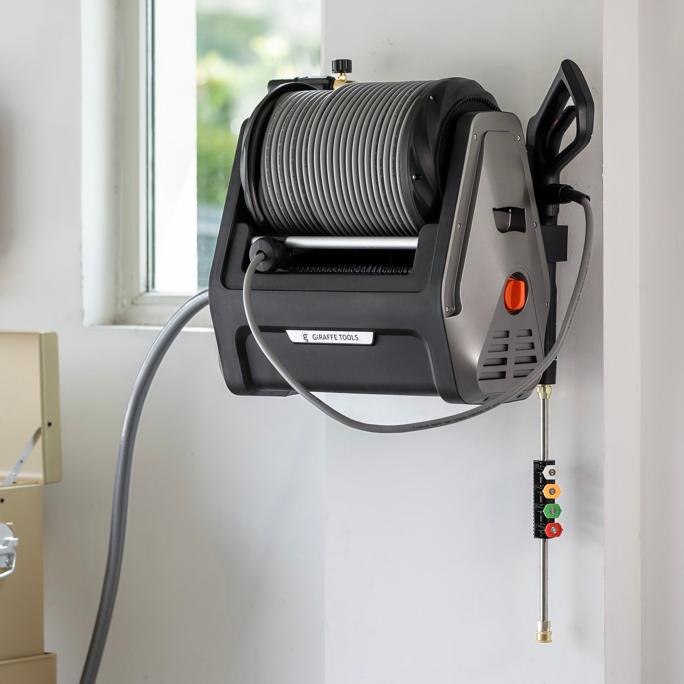 Giraffe Tools Grandfalls Retractable Pressure Washer Plus Features showing wall-mounted installation with organized spray gun and nozzle storage for a tidy cleaning space