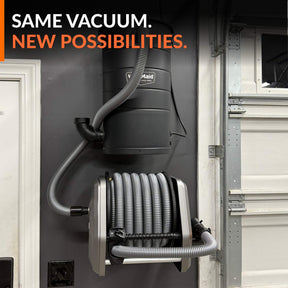 Wall-mounted vacuum hose reel connected to an existing vacuum in a garage.