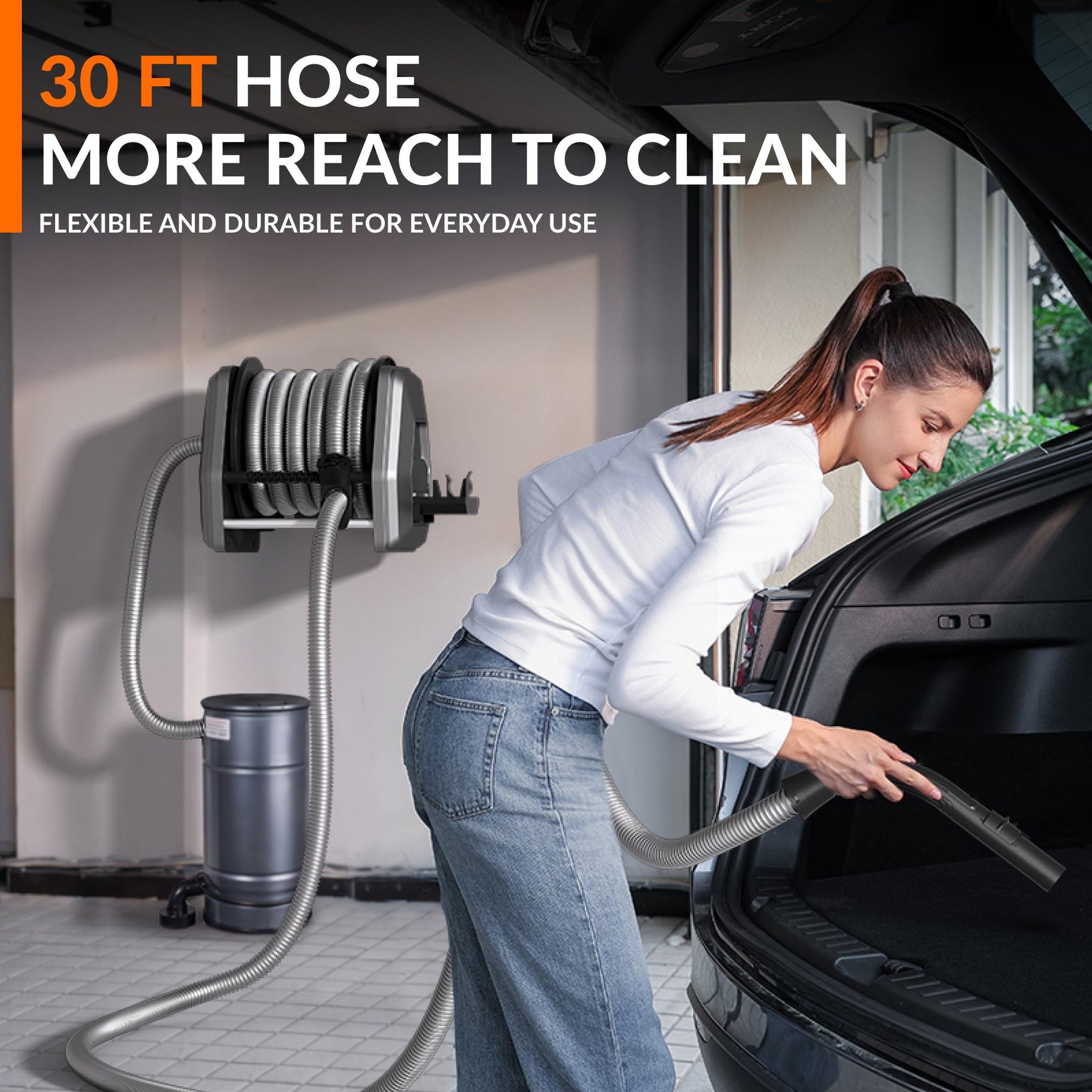 Woman using the 30 ft vacuum hose to clean a car trunk.